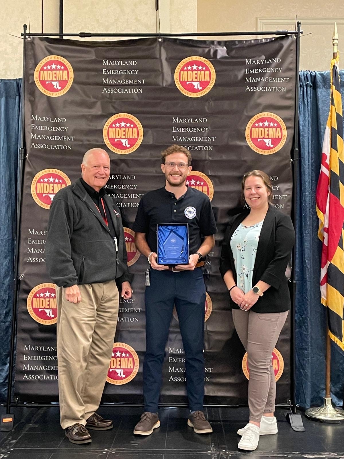 Emergency Manager of the Year Award Winner standing next to Secretary Russ Strickland and President of the Maryland Emergency Management Association, Emily Wesslehoff.